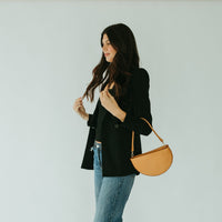 Woman holding a brown handbag against a plain background