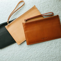Three leather bags in black, beige, and brown on a textured surface