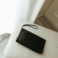 Black clutch bag on a textured surface with a blurred background