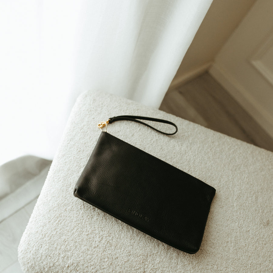 Black clutch bag on a textured surface with a blurred background