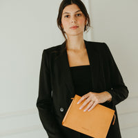 Woman holding a brown leather clutch against a white background