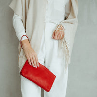 Person holding a red clutch with a neutral background