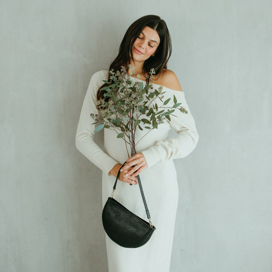 Woman in a white off-shoulder dress holding a bouquet against a plain background